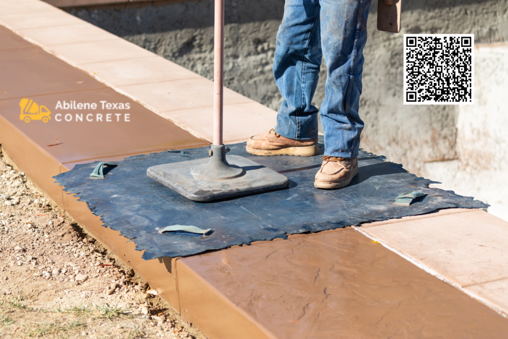 An expert concrete contractor in Abilene pressing a design stamp into cement.