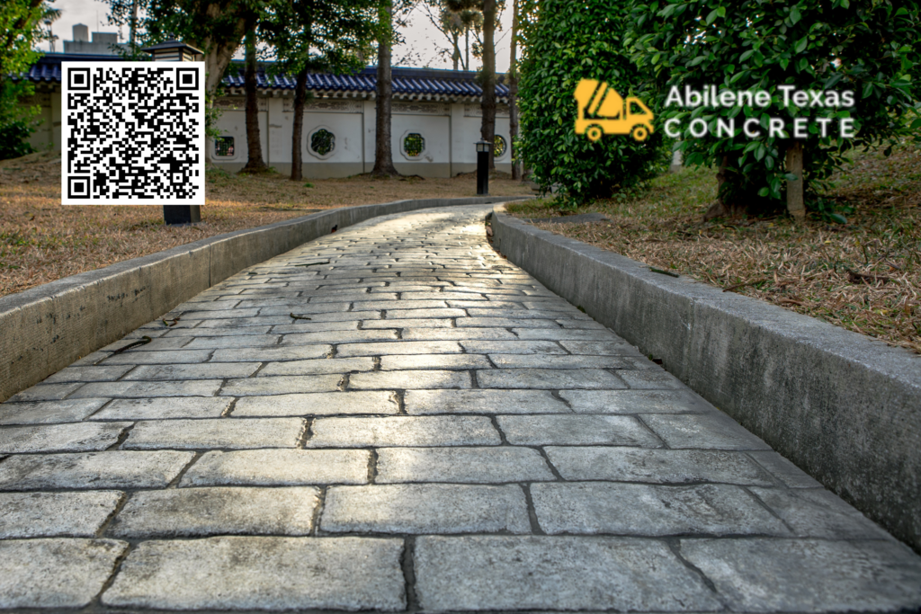 A concrete hardscape walkway in front of a house.